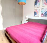 LUXUSNÝ 3i byt, TERASA, PARKING, KLÍMA, ZELENÁ HORKA, Ďumbierska ulica - Spálňa v 2-izbovom byte s farebným obrazom na stene a podlahou s dreveným dekorom.