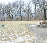 LUXUSNÝ 3i byt, TERASA, PARKING, KLÍMA, ZELENÁ HORKA, Ďumbierska ulica - Zasnežená plocha s lavičkou a fúrikom, obklopená stromami.