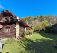 Šikovná drevenica pod lesom Slovenské Pravno  - Rodinný dom v Slovenskom Pravne z dreva a kameňa, strom, zeleň, modrá obloha.