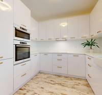 4-izbový byt 92m2 + terasa 14m2 | Bernolákovo - Kuchyňa 4-izbového bytu s bielymi skrinkami a podlahou s dreveným dekorom.