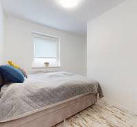 4-izbový byt 92m2 + terasa 14m2 | Bernolákovo - Spálňa s posteľou a dekoratívnymi vankúšmi, podlaha s dreveným dekorom v 4-izbovom byte.