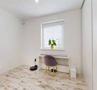 4-izbový byt 92m2 + terasa 14m2 | Bernolákovo - Izba v 4-izbovom byte s klavírom, stoličkou a podlahou s dreveným dekorom.