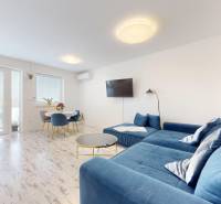 4-izbový byt 92m2 + terasa 14m2 | Bernolákovo - Obývačka v 4-izbovom byte s modrou sedačkou a podlahou s dreveným dekorom.