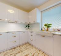 4-izbový byt 92m2 + terasa 14m2 | Bernolákovo - Kuchyňa v 4-izbovom byte s bielou linkou a podlahou s dreveným dekorom.