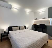 Bez provízie | Na prenájom dizajnové štúdio v Ružinove - Spálňa s podlahou s dreveným dekorom, dvojposteľou a kuchynským kútom v garsónke.