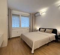 Bez provízie | Na prenájom dizajnové štúdio v Ružinove - Spálňa v garsónke s posteľou, klimatizáciou a podlahou s dreveným dekorom.