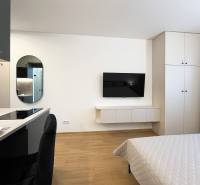 Bez provízie | Na prenájom dizajnové štúdio v Ružinove - Garsónka s TV na stene, podnikoverská podlaha, posteľ a kuchyňa.