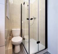 Bez provízie | Na prenájom dizajnové štúdio v Ružinove - Kúpeľňa v garsónke s toaletou a sprchovacím kútom, dlažba svetlej farby.