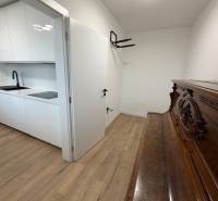 3 izbový byt s balkónom Topoľčany / PRENAJOM  - Biela kuchyňa s dreveným dekorom podlahy, vedľa klavír, 3-izbový byt.