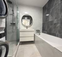 3 izbový byt s balkónom Topoľčany / PRENAJOM  - Kúpeľňa v 3-izbovom byte s vaňou, práčkou a okrúhlym zrkadlom nad umývadlom.