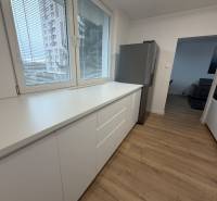 3 izbový byt s balkónom Topoľčany / PRENAJOM  - Kuchyňa 3-izbového bytu s bielymi skrinkami a podlahou s dreveným dekorom.