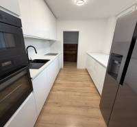 3 izbový byt s balkónom Topoľčany / PRENAJOM  - Kuchyňa s bielymi skrinkami, čiernymi spotrebičmi a podlahou s dreveným dekorom v 3-izbovom byte.