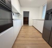 3 izbový byt s balkónom Topoľčany / PRENAJOM  - Kuchyňa s bielymi skrinkami a podlahou s dreveným dekorom v 3-izbovom byte.