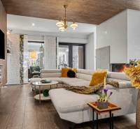 Ideálny dom pre rodinu, Blatné, okr. Senec - Obývačka v rodinnom dome s pohovkou, krbom a podlahou s dreveným dekorom.