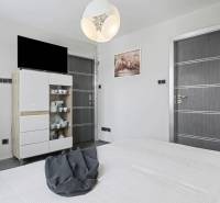 Ideálny dom pre rodinu, Blatné, okr. Senec - Spálňa v rodinnom dome s nábytkom, televízorom a dekoračným osvetlením.