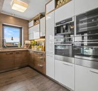 Ideálny dom pre rodinu, Blatné, okr. Senec - Kuchyňa v Rodinnom dome s podlahou s dreveným dekorom a modernými spotrebičmi.