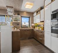 Ideálny dom pre rodinu, Blatné, okr. Senec - Kuchyňa v rodinnom dome s podlahou s dreveným dekorom, modernými spotrebičmi a dekoratívnym osvetlením.