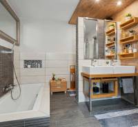 Ideálny dom pre rodinu, Blatné, okr. Senec - Kúpeľňa v rodinnom dome s vaňou, dvoma umývadlami a policami, podlaha s dreveným dekorom.