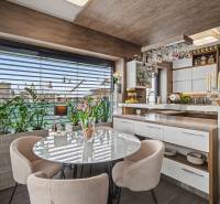Ideálny dom pre rodinu, Blatné, okr. Senec - Kuchyňa v rodinnom dome s presklením, rastlinami a stolom s kreslami, podlaha s dreveným dekorom.