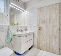Unikátna 4i NOVOSTAVBA, Špačince 740m² pozemok len pár minút od Trnavy - Kúpeľňa v rodinnom dome s umývadlom, zrkadlom a toaletou. Biele obklady a drevené dvere.