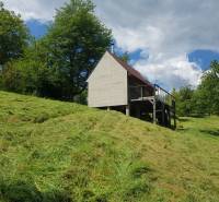 Na predaj záhradná chatka - Chata na ulici Na Gremenici v Žarnovici obklopená zeleným svahom a stromami.