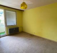 Na predaj veľký 3-izbový byt s lodžiou v Detve - Novosady - Izba v 3-izbovom byte so žltými stenami, otvoreným balkónom a radiátorom.