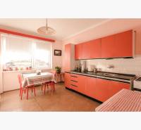 Dvojgeneračný rodinný dom s potenciálom | 2 bytové jednotky, TV - Kuchyňa v rodinnom dome s oranžovými skrinkami a podlahou s dreveným dekorom.