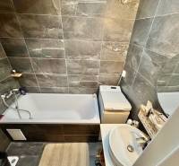 Veľký 2-izb. byt v tehlovom dome, Ružová dolina, Ružinov časť Nivy - Kúpeľňa v 2-izbovom byte s vaňou, umývadlom a tmavými obkladmi stien.