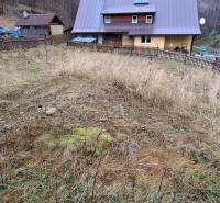 Lukratívny stavebný pozemok - Pozemok na bývanie v Oščadnici so svahovitým terénom a susednými domami v pozadí.