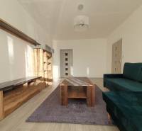 KH-1052, 3 izbový byt, Košice – Staré Mesto, širšie centrum, Kuzmányho - Obývacia izba v 3-izbovom byte s pohovkou, skriňou a stolíkom na podlahe s dreveným dekorom.