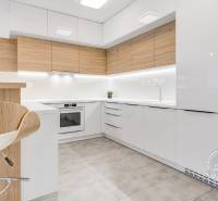 ŠPIČKOVO KOMPLETNE ZARIADENÝ 2-izb. byt bez kompromisov - Kuchyňa s bielymi skrinkami, dreveným dekorom a bielymi stoličkami v 2-izbovom byte.