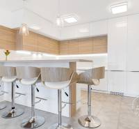 ŠPIČKOVO KOMPLETNE ZARIADENÝ 2-izb. byt bez kompromisov - Kuchyňa s barovými stoličkami a podlahou s dreveným dekorom v 2-izbovom byte.