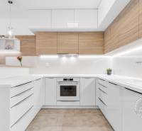 ŠPIČKOVO KOMPLETNE ZARIADENÝ 2-izb. byt bez kompromisov - Svetlá kuchyňa v 2-izbovom byte s dreveným dekorom a bielymi skrinkami.
