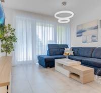 ŠPIČKOVO KOMPLETNE ZARIADENÝ 2-izb. byt bez kompromisov - Obývacia izba v 2-izbovom byte s modrou sedačkou, televíziou a dekoráciou rastlín.