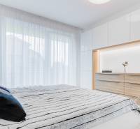 ŠPIČKOVO KOMPLETNE ZARIADENÝ 2-izb. byt bez kompromisov - Spálňa v 2-izbovom byte so závesmi, dekou a komodou s dreveným dekorom.