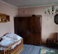 Predaj 4 izbový rodinný dom Šulekovo  - Izba rodinného domu s pohovkou, skriňou, lustrom a poličkou na stenách.