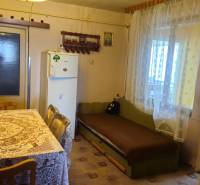 Predaj 4 izbový rodinný dom Šulekovo  - Kuchyňa v rodinnom dome s obrusom na stole, pohovkou a chladničkou.