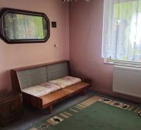 Predaj 4 izbový rodinný dom Šulekovo  - Izba v rodinnom dome s pohovkou, zeleným kobercom a ornamentálnou záclonou.