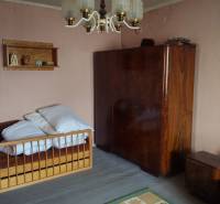 Predaj 4 izbový rodinný dom Šulekovo  - Izba v rodinnom dome s posteľou, skriňou a lustrom, steny sú svetlo ružové.