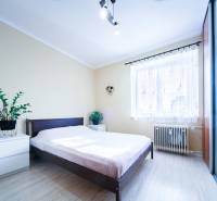 Kompletne zrekonštruovaný 3-izbový byt s balkónom – Rimavská Sobota - Svetlá spálňa s posteľou, zrkadlovou skriňou a podlahou s dreveným dekorom v 3-izbovom byte.