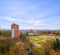 Kompletne zrekonštruovaný 3-izbový byt s balkónom – Rimavská Sobota - Výhľad z 3-izbového bytu na Rožňavskej ulici v Rimavskej Sobote, vysoké bytové domy, parkovisko.