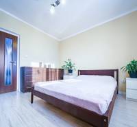 Kompletne zrekonštruovaný 3-izbový byt s balkónom – Rimavská Sobota - Spálňa v 3-izbovom byte s posteľou, komodou a podlahou s dreveným dekorom.