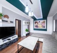 Kompletne zrekonštruovaný 3-izbový byt s balkónom – Rimavská Sobota - Obývačka v 3-izbovom byte s podlahou s dreveným dekorom, moderným nábytkom a umeleckým obrazom.