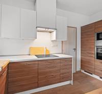 PRENÁJOM 3i byt s veľkorysou terasou a súkromím – Staré Grunty - Kuchyňa v 3-izbovom byte s drevenými skrinkami a podlahou s dreveným dekorom.