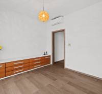 PRENÁJOM 3i byt s veľkorysou terasou a súkromím – Staré Grunty - Interiér 3-izbového bytu s podlahou s dreveným dekorom, svetelným lustre a komodou.