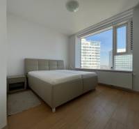 NUERA︱PANORAMA CITY- Veľký 3-izbový byt s výhľadom na hrad - Spálňa v 3-izbovom byte s posteľou, nočným stolíkom a podlahou s dreveným dekorom.