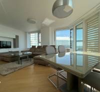 NUERA︱PANORAMA CITY- Veľký 3-izbový byt s výhľadom na hrad - Obývačka v 3-izbovom byte s podlahou s dreveným dekorom, veľkým oknom a sedačkou.