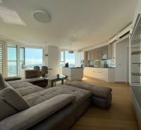 NUERA︱PANORAMA CITY- Veľký 3-izbový byt s výhľadom na hrad - Obývacia izba s kuchyňou a podlahou s dreveným dekorom v 3-izbovom byte.