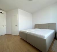 NUERA︱PANORAMA CITY- Veľký 3-izbový byt s výhľadom na hrad - Spálňa so svetlou posteľou, nočným stolíkom a podlahou s dreveným dekorom v 3-izbovom byte.