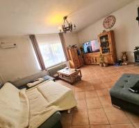 5.izb RD Čereňany pozemok 1028m - Obývacia izba s krbovými kachľami, dlažbou a dreveným nábytkom v rodinnom dome.